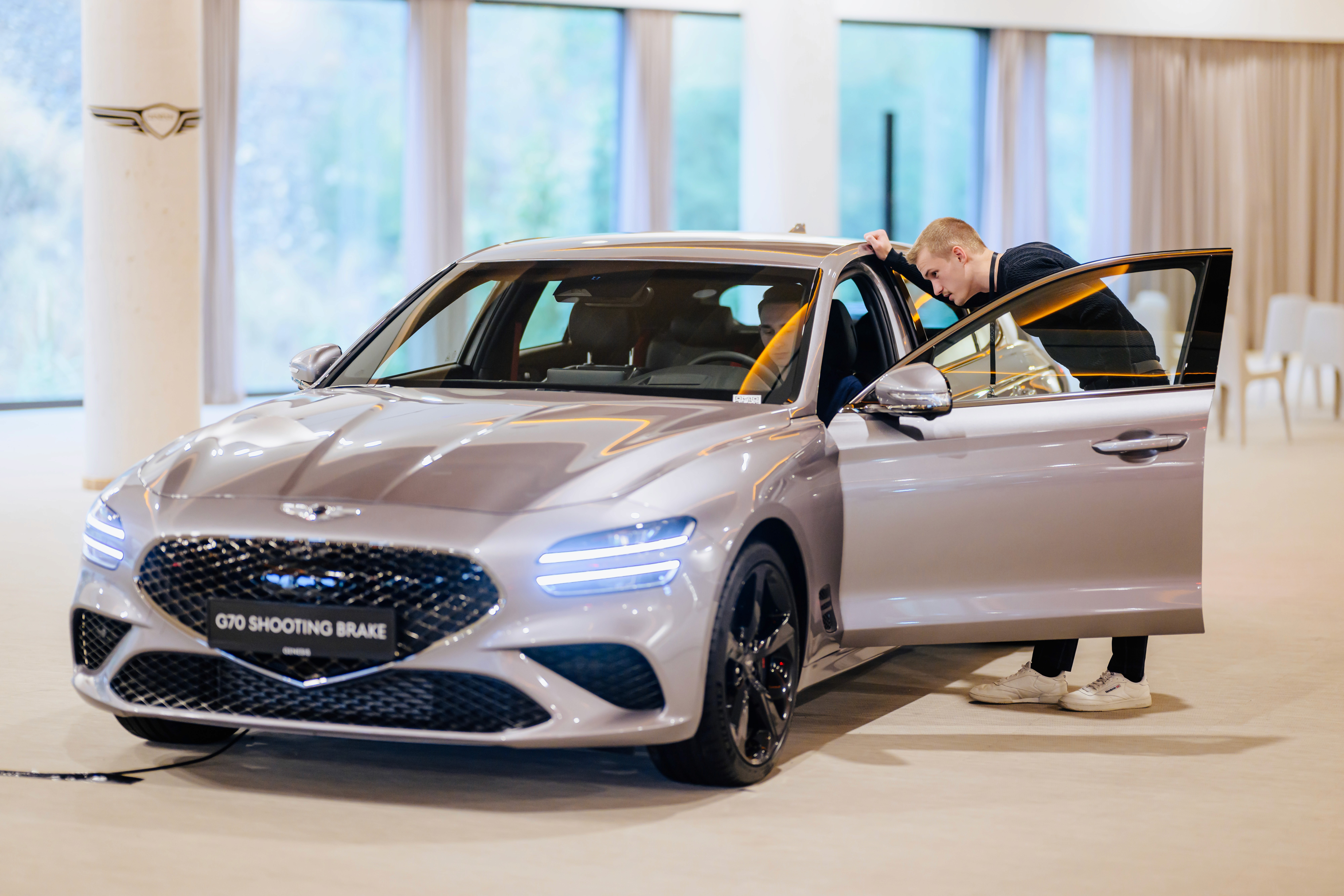 Eventteilnehmer inspiziert das Interieur eines Genesis G70 Shooting Brake während exklusivem Testdrive-Event im Showroom.