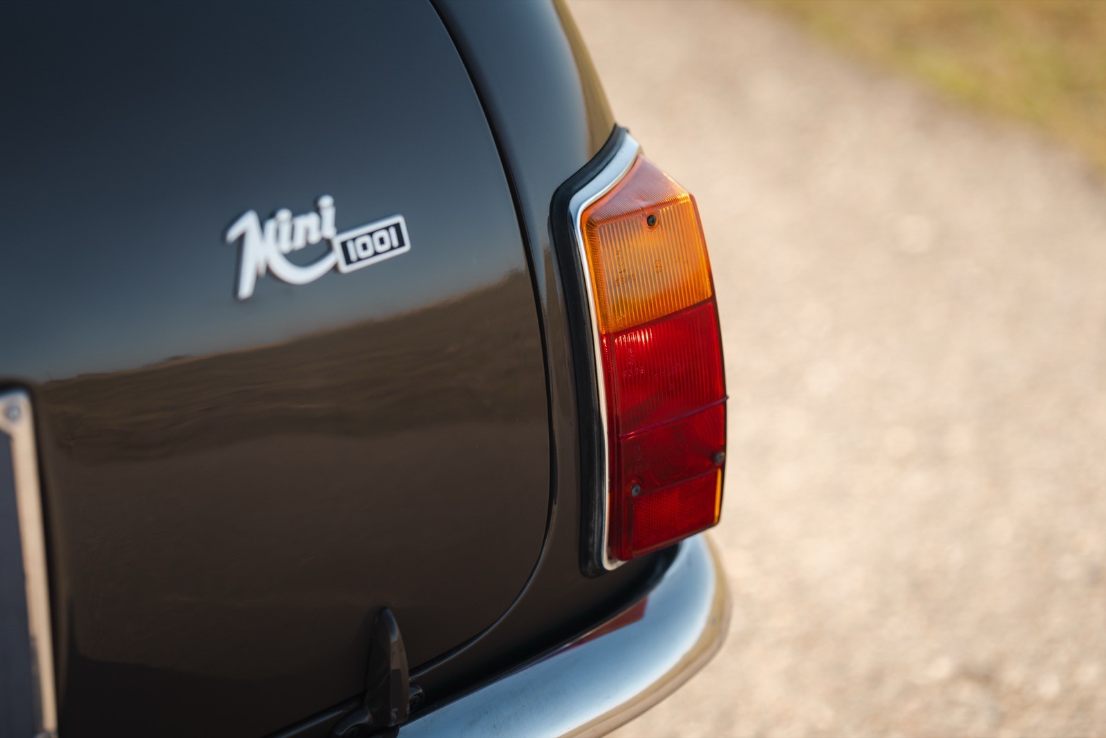 Close-up of the rear of a vintage car, showing the tail light and a logo on dark paint.