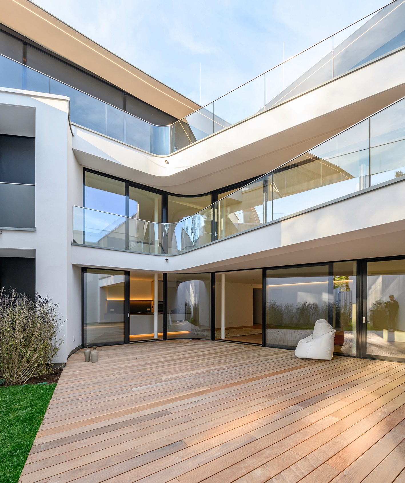 Die Geometrien des neu errichteten Wohngebäudes in Wien Döbling nehmen sehr klar die Bezüge zum historischen, baukulturellen Kontext und zur bestehenden Umgebung auf; durch die Positionierung des Baukörpers horizontal zum Hang werden diese fortgeführt. Die einzelnen Gebäudetrakte, welche insgesamt sieben Wohneinheiten umfassen, wurden rund um einen weitläufigen Garten-Innenhof mit Schwimmbad angeordModernes weißes Wohnhaus in der Armbrustergasse mit großer Holzterrasse, bodentiefen Fenstern und Glasgeländern auf zwei Etagen.