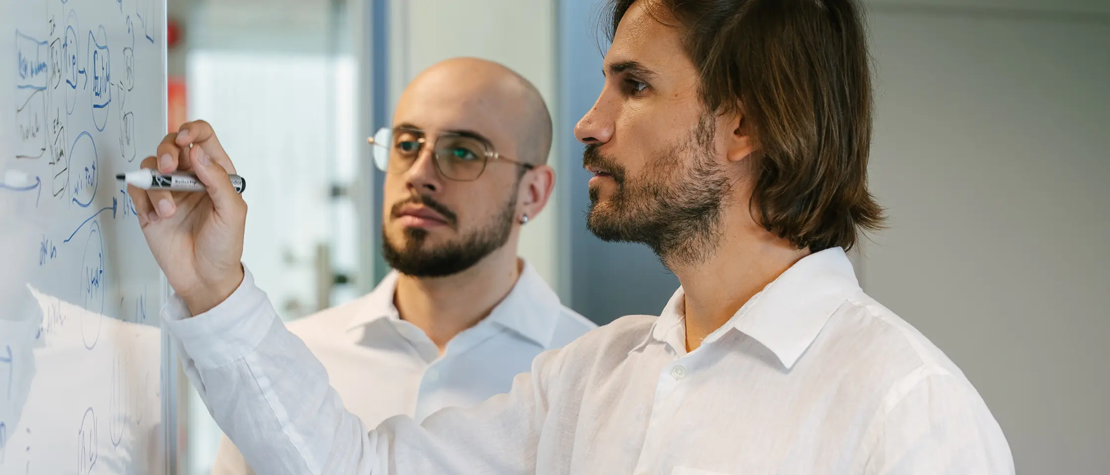 Dos personas comentando datos escritos en una pizarra