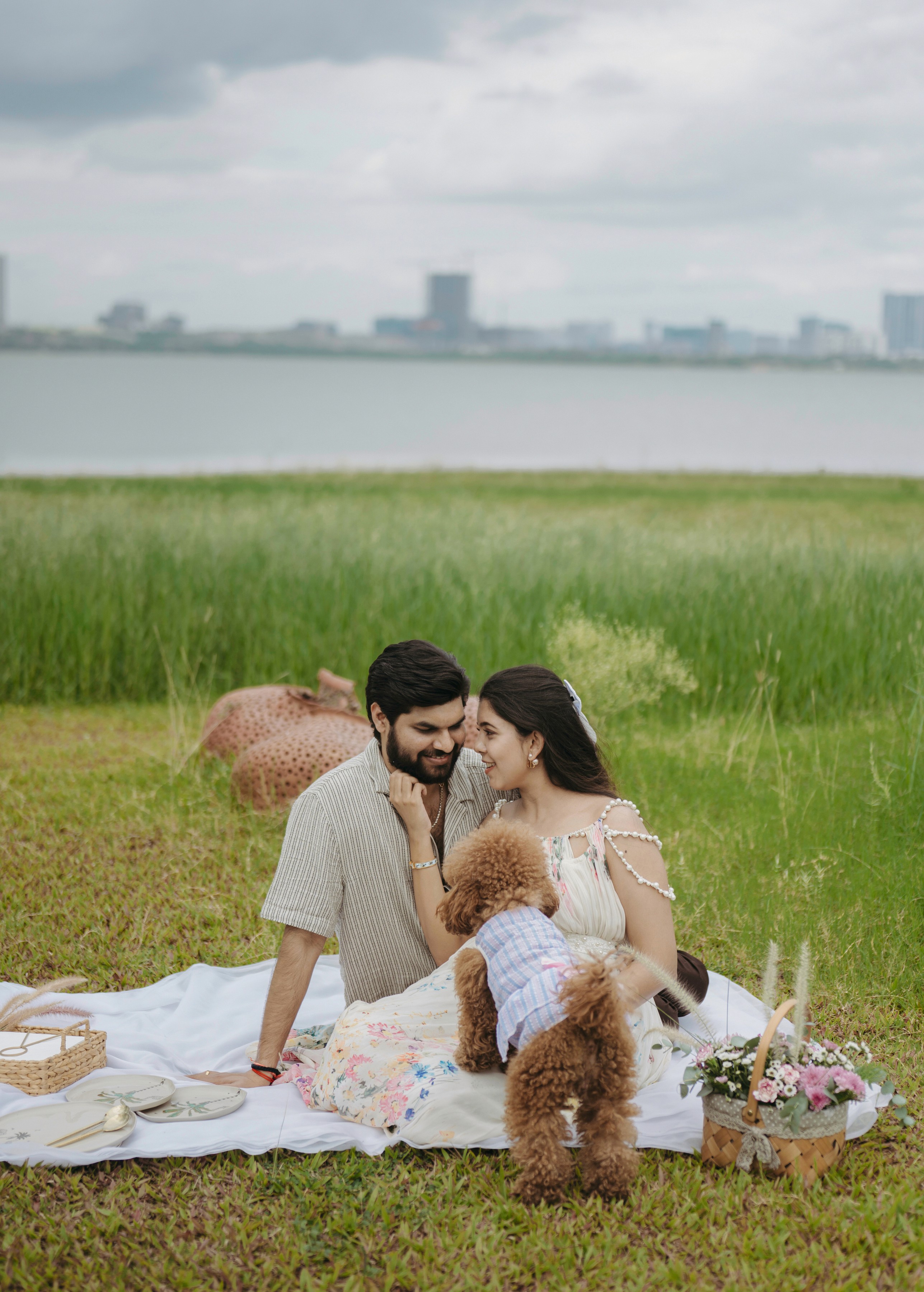 Maternity photoshoot of couple in traditional attire against a floral backdrop, captured by Wow Makers in Hyderabad, India.