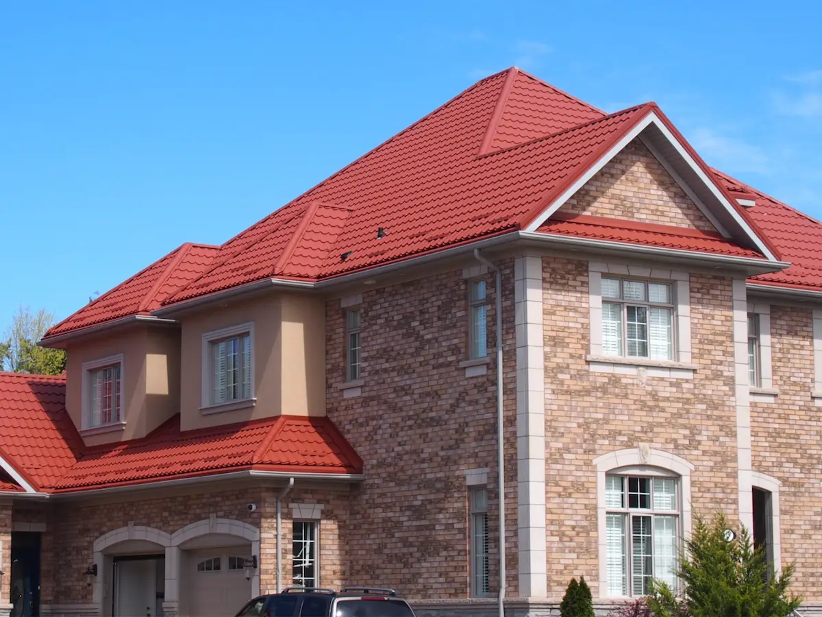 Toiture en tuiles métalliques rouges sur maison résidentielle en briques à Montréal