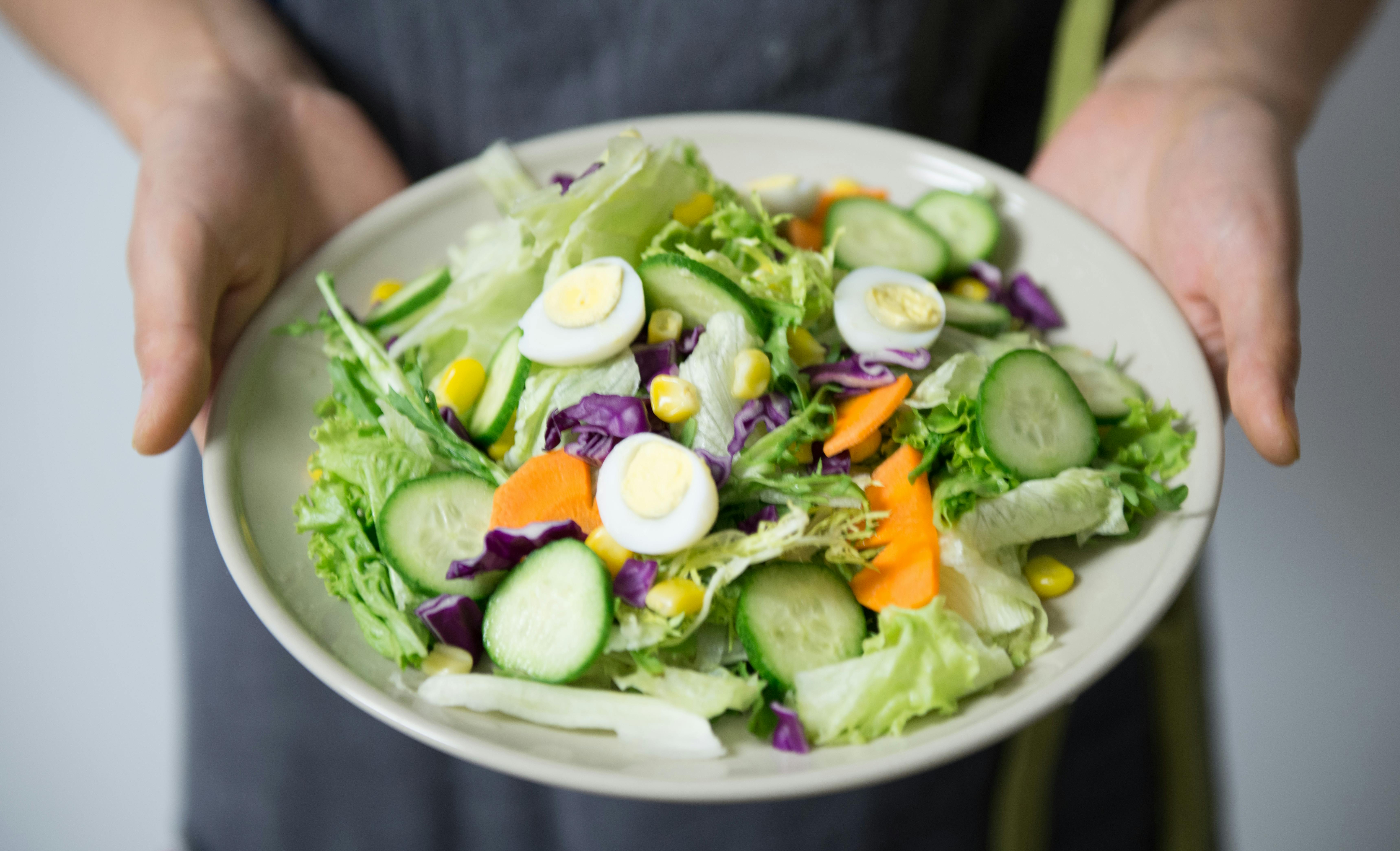 Fresh bowl of mixed salad with cucumbers, eggs, carrots, and leafy greens