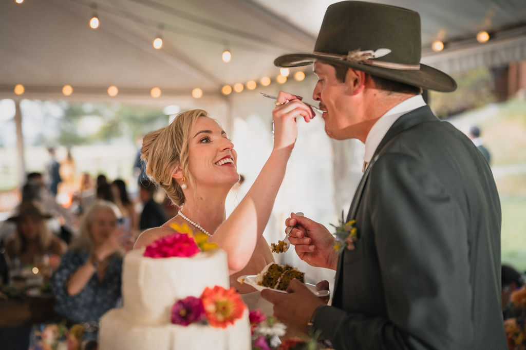 Newlyweds feeding each other cake at the reception