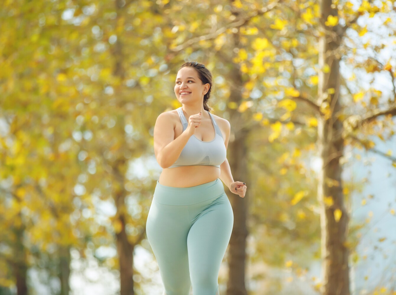 smiling woman having fun by doing a run to lose weight plan outside at a park