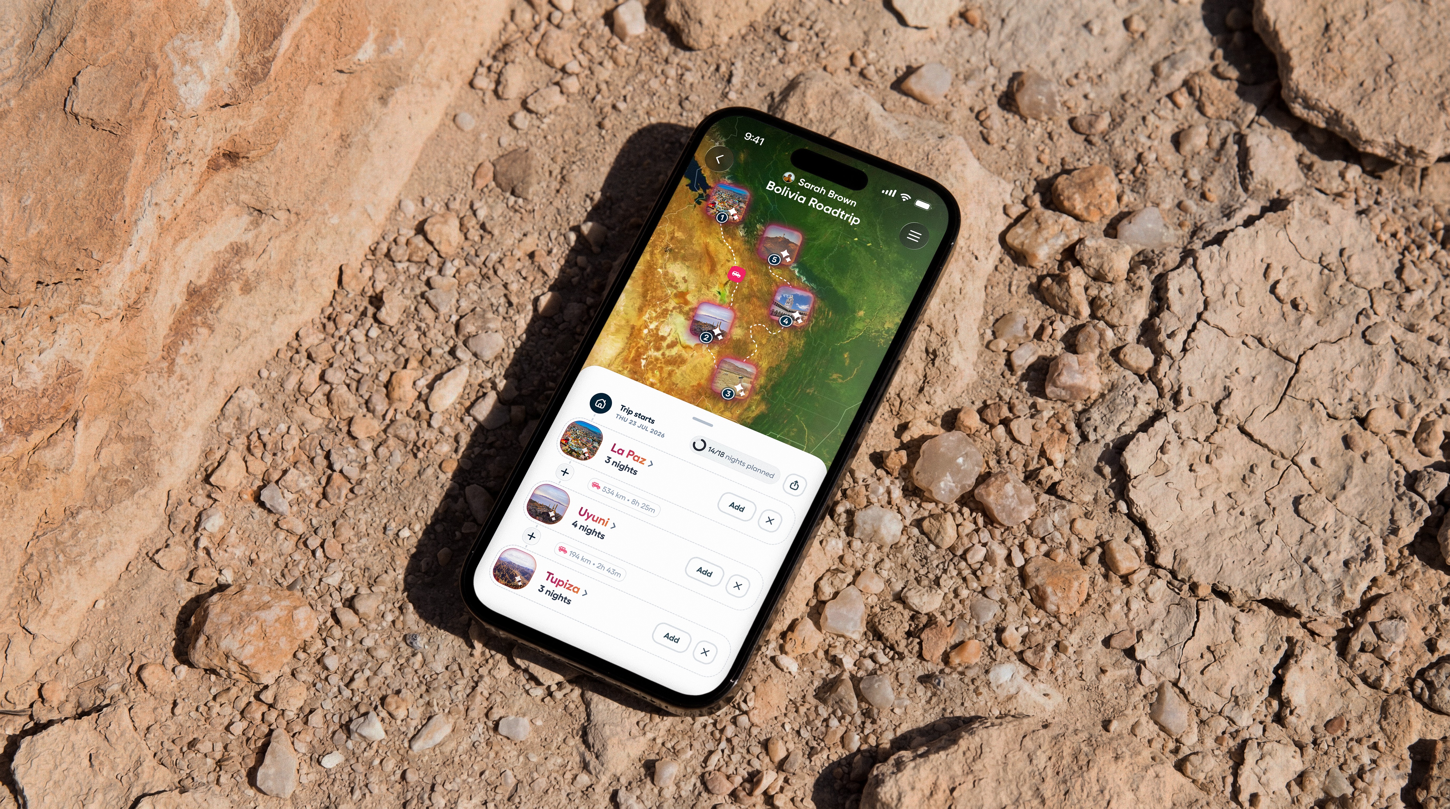 A group of people are skiing along a piste beside trees laden with snow.