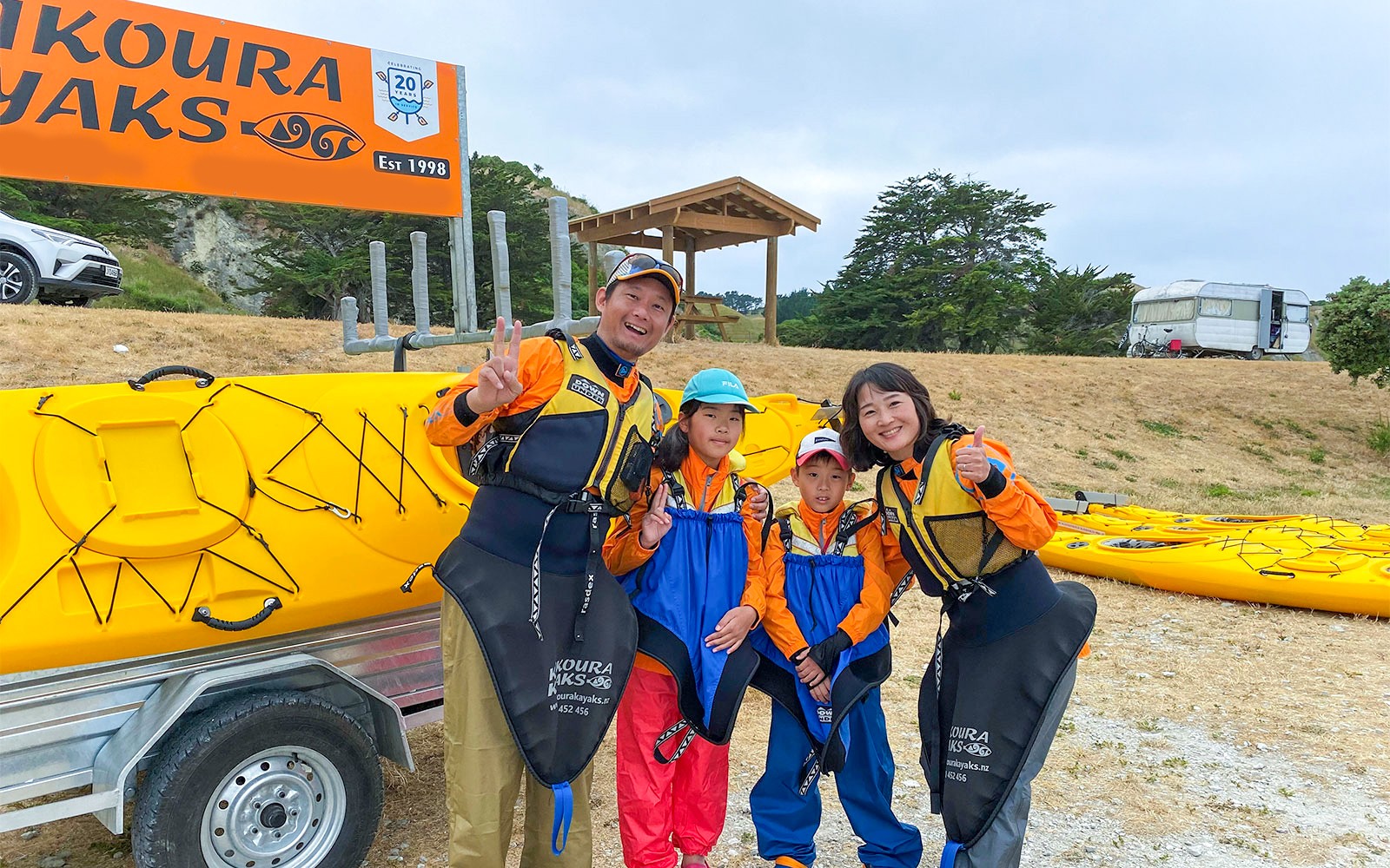 Familie bereit für ein Kajak-Abenteuer in Kaikoura, Neuseeland, steht neben gelben Kajaks.