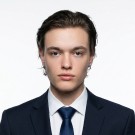 Portrait of a woman with long, smooth hair swept to the side, in a dark t-shirt, on a plain background.