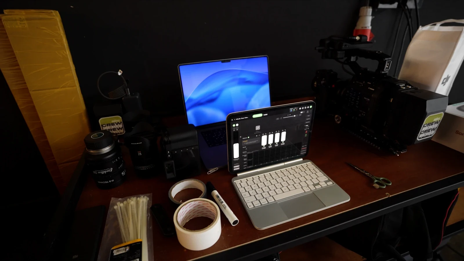 Production desk with a laptop, iPad lighting control, cinema lenses and a Canon cinema camera