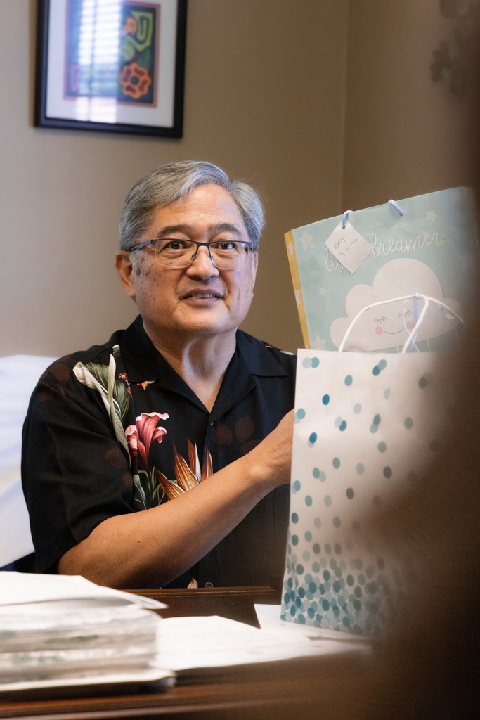 Pediatrician man holding gift bag for children, speaking to caretaker.