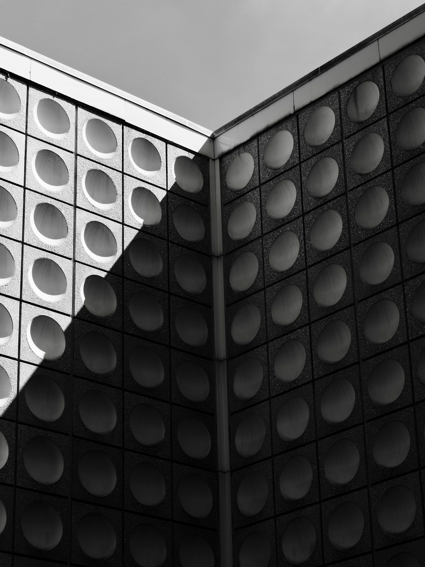 Facade of circular recesses half in shadow
