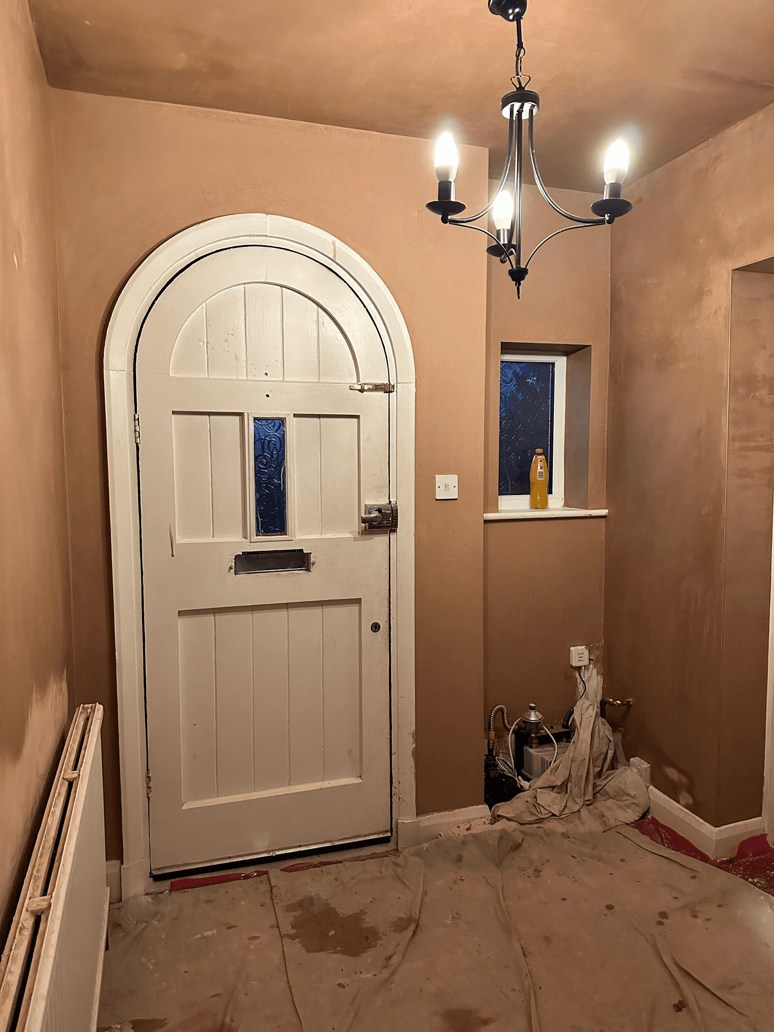 Fully plastered hallway with arched door.