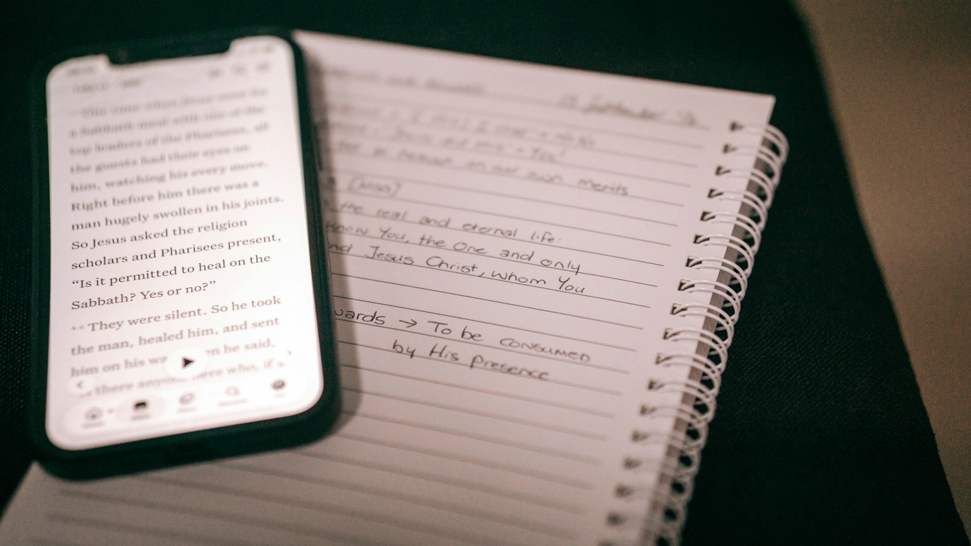 phone photographing a handwritten notebook page on a table
