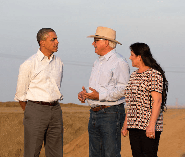 President Obama standing with a farmer and his wife outside.