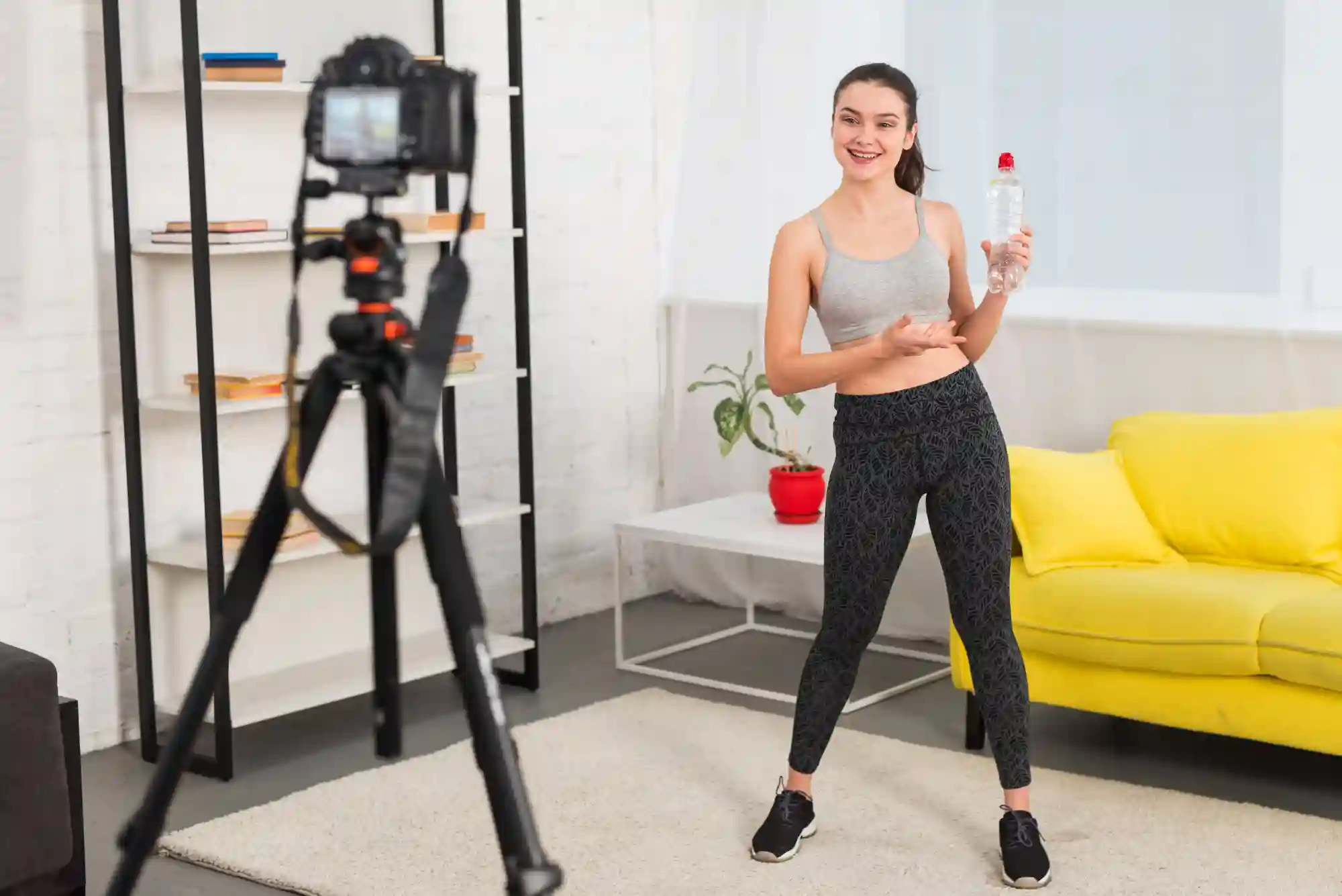 Female fitness influencer recording a workout or health-related video and holding a water bottle.
