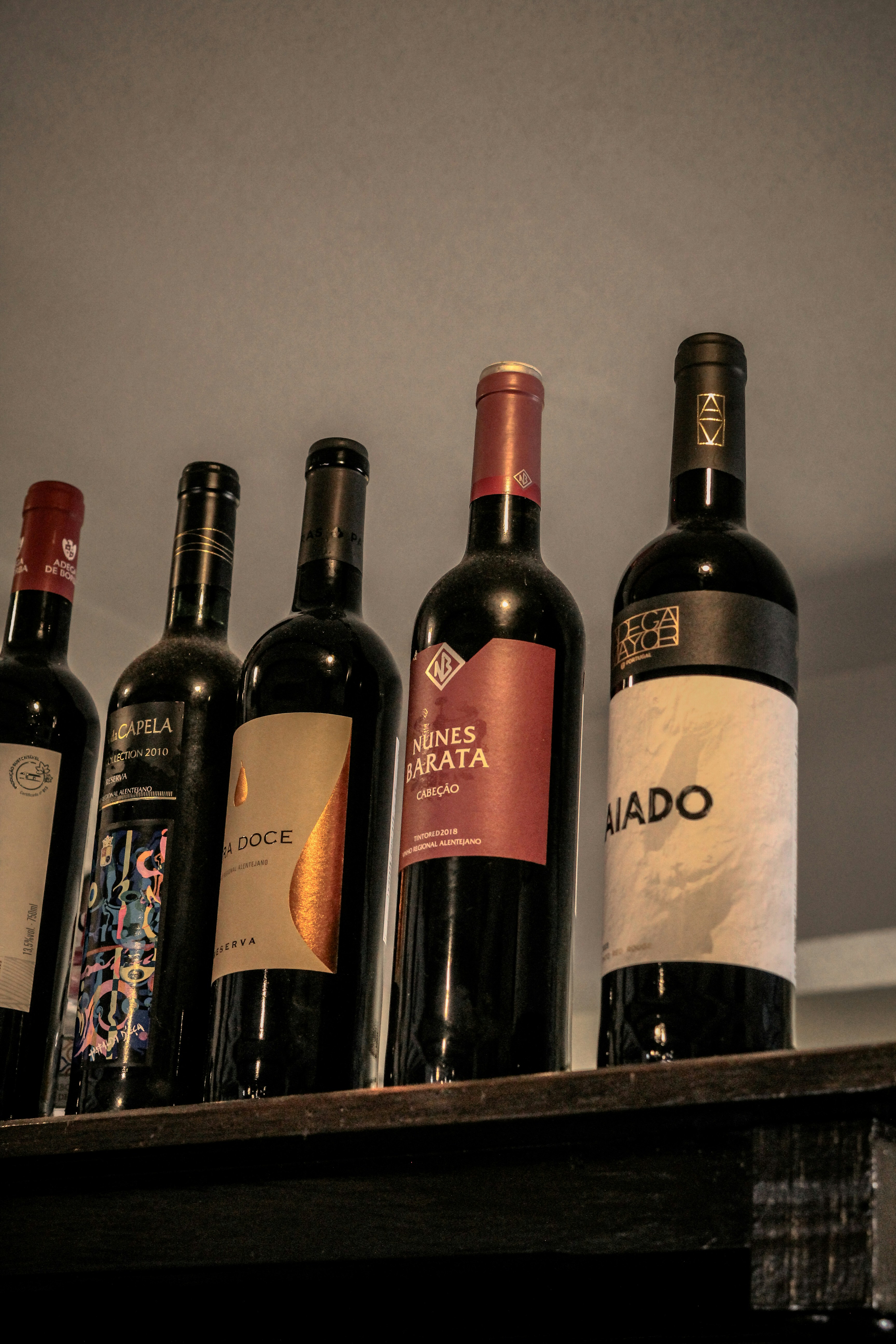 Several bottles of wine lined up on a shelf.