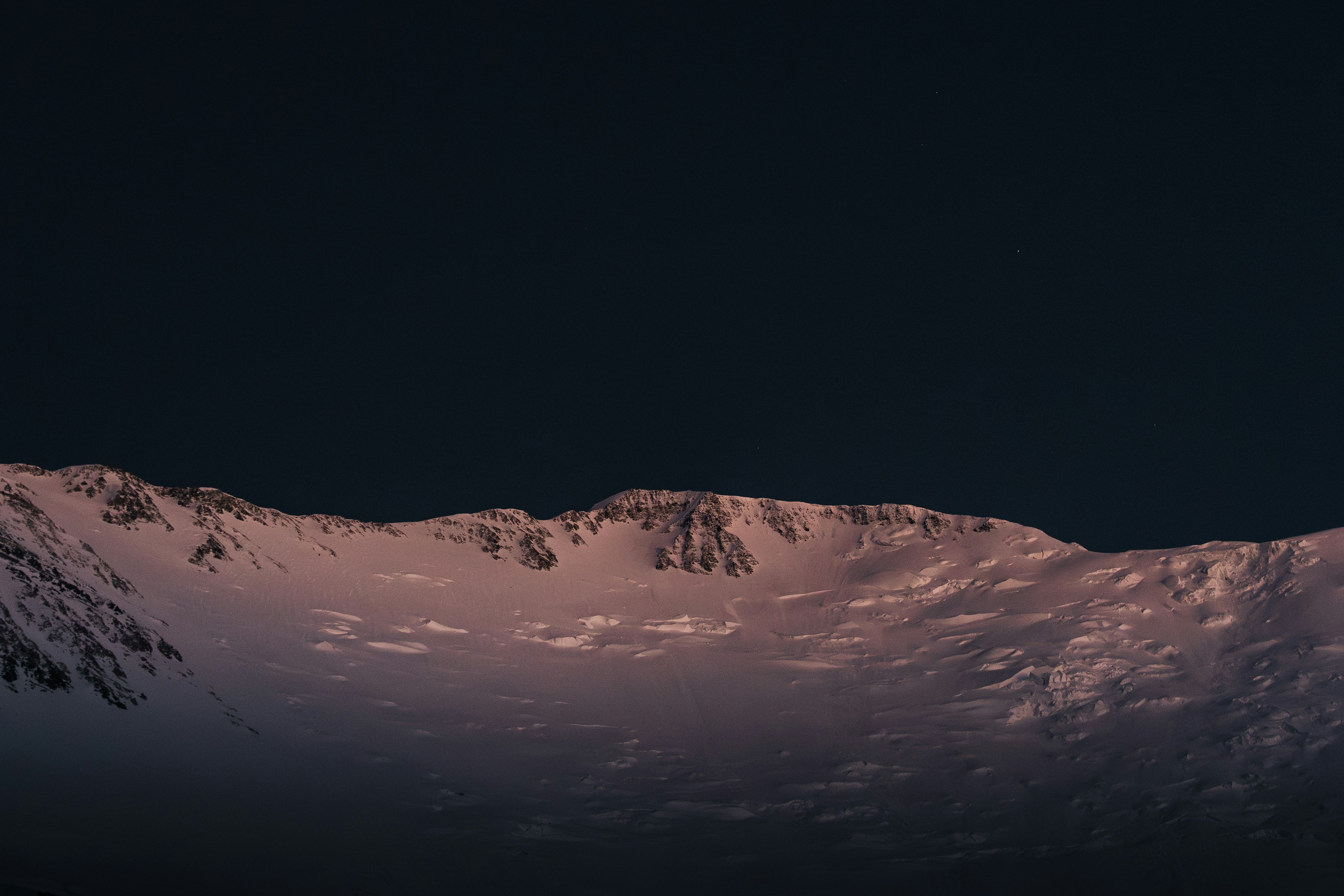 Snowy mountain range under a dark starry sky