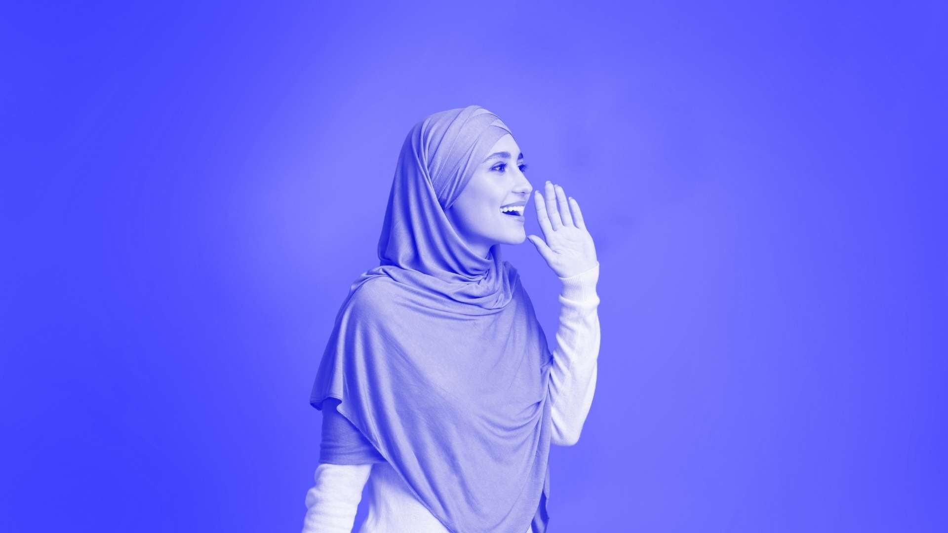 Lady wearing a hijab calling out with her hand by her face