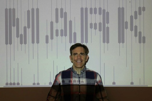 portrait of a man against a wall, and he has an image projected on the wall and himself