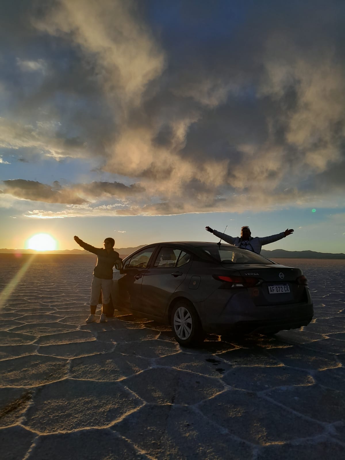Mujer sentada sobre un tronco frente a una cascada doble en un bosque frondoso de Argentina.