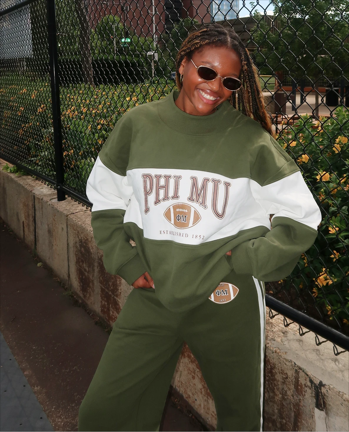 Alex Ruff wearing an olive-and-cream Phi Mu football sweatshirt with matching wide-leg pants.