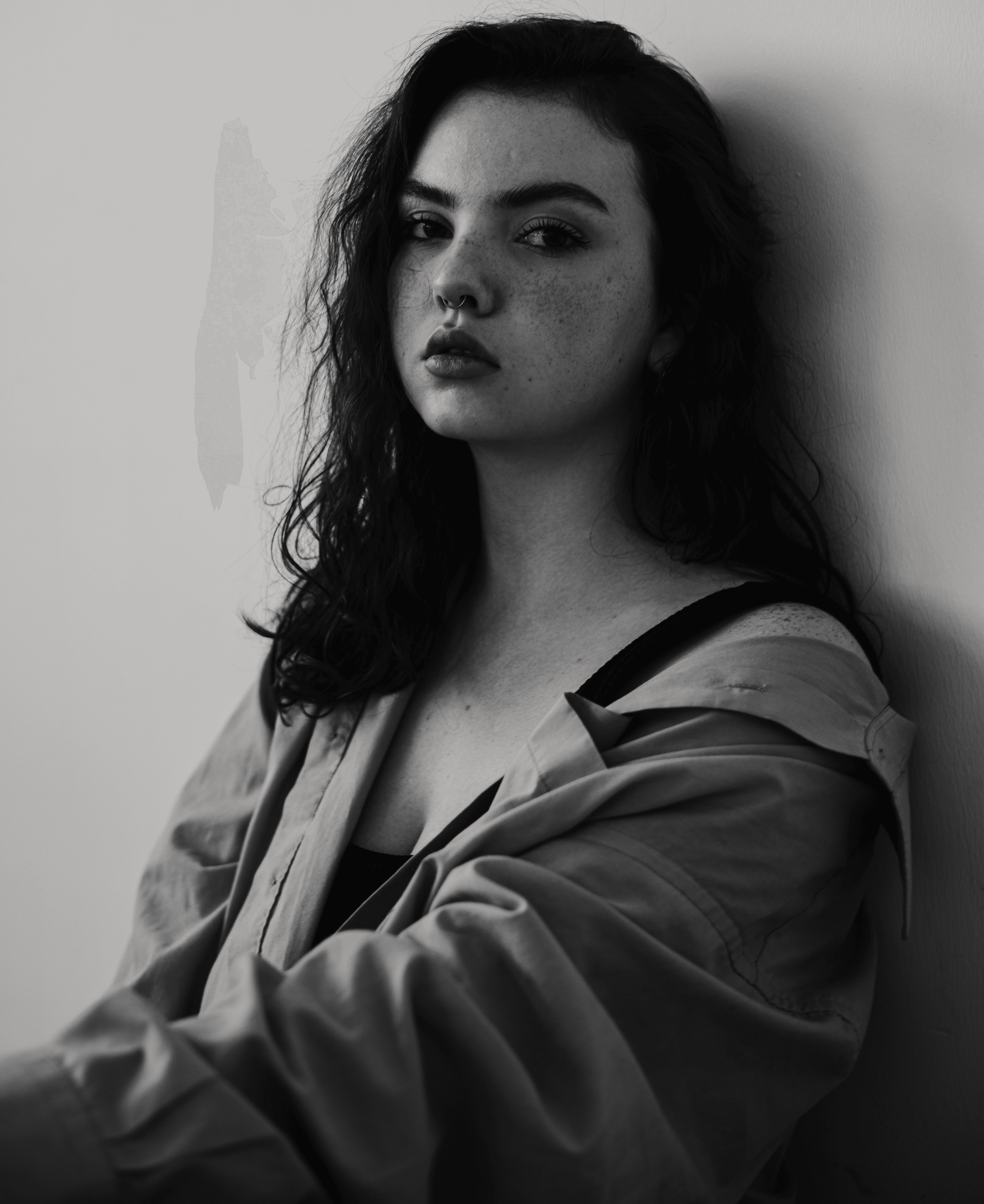 a black and white photo of a woman leaning against a wall