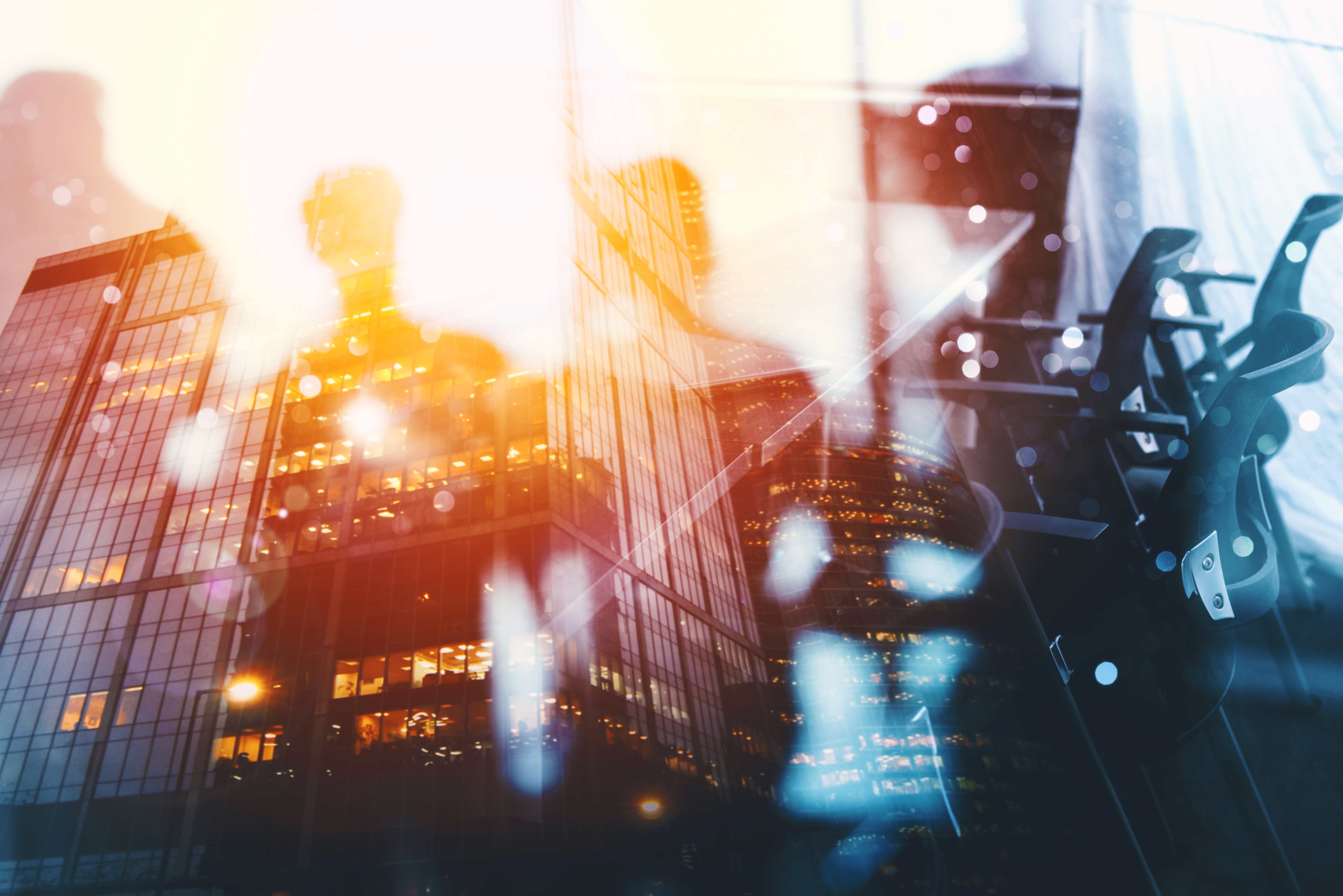 A smiling young man with crossed arms, wearing a plaid shirt and white t-shirt, poses against a dark background.