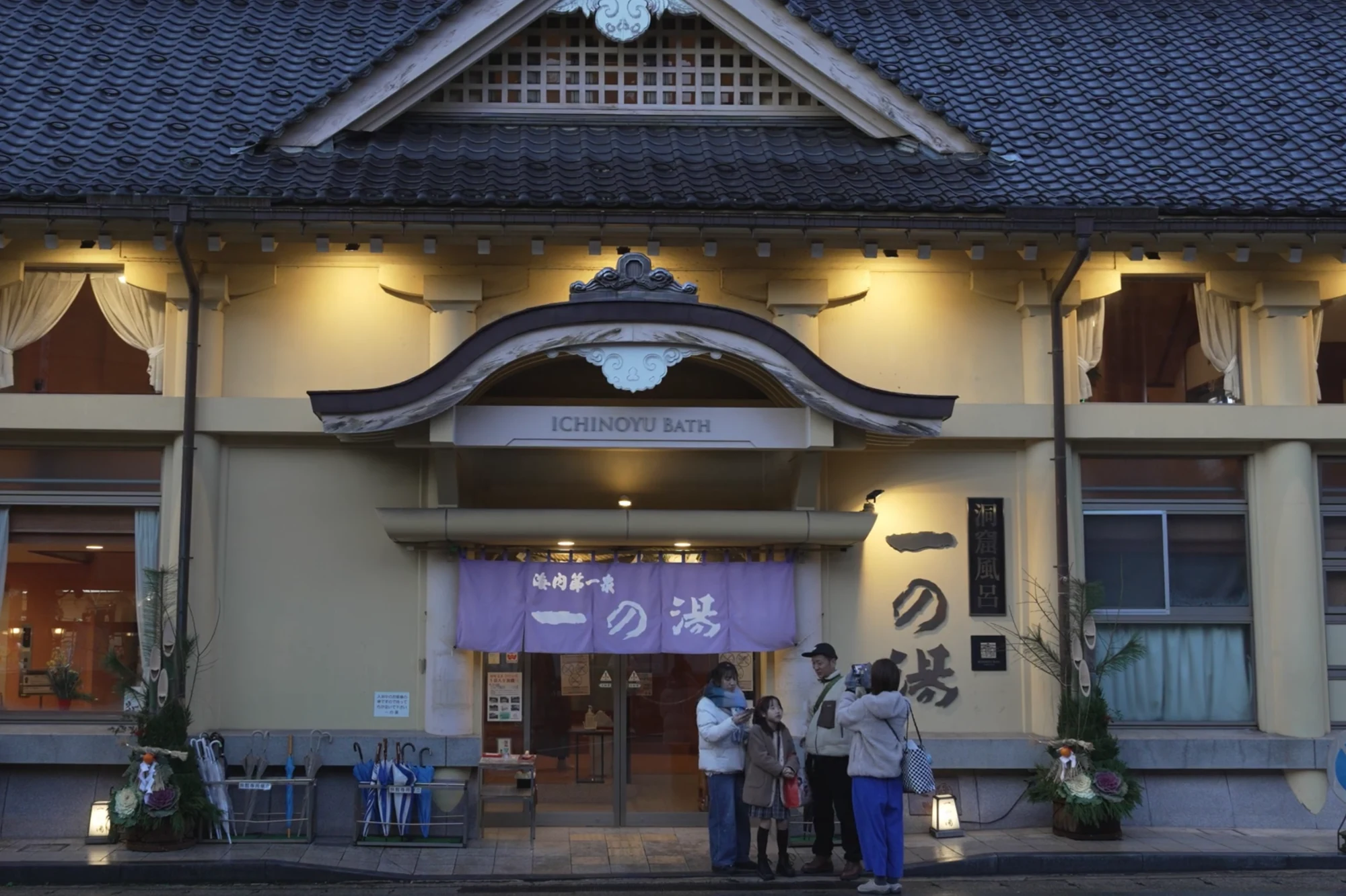 The pale-yellow facade of Ichi-no-yu bathhouse in Kinosaki lit at dusk.