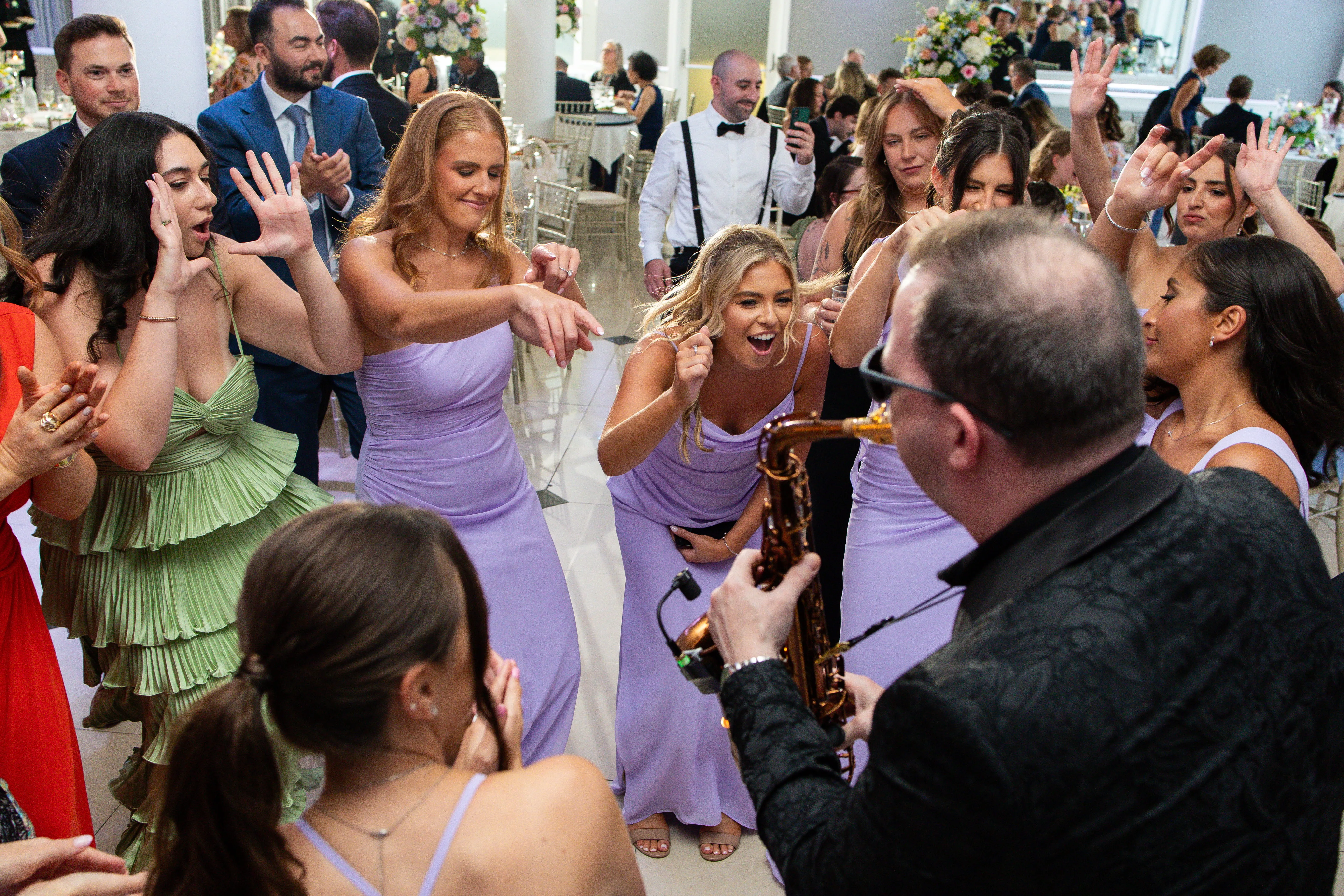 Wedding guests dancing on packed dance floor with DJ creating high energy reception atmosphere