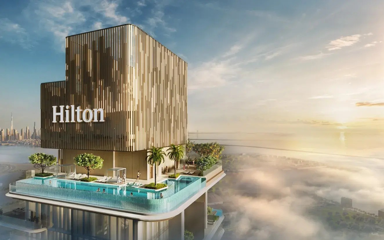 Hilton Residences tower sign with an infinity pool deck high above the clouds, offering a stunning Dubai skyline view at sunset.