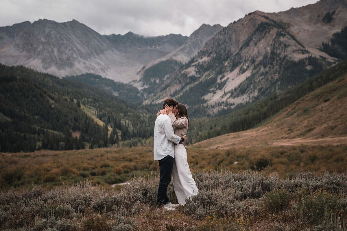 Couple enjoying a winter engagement session in a snowy Aspen grove