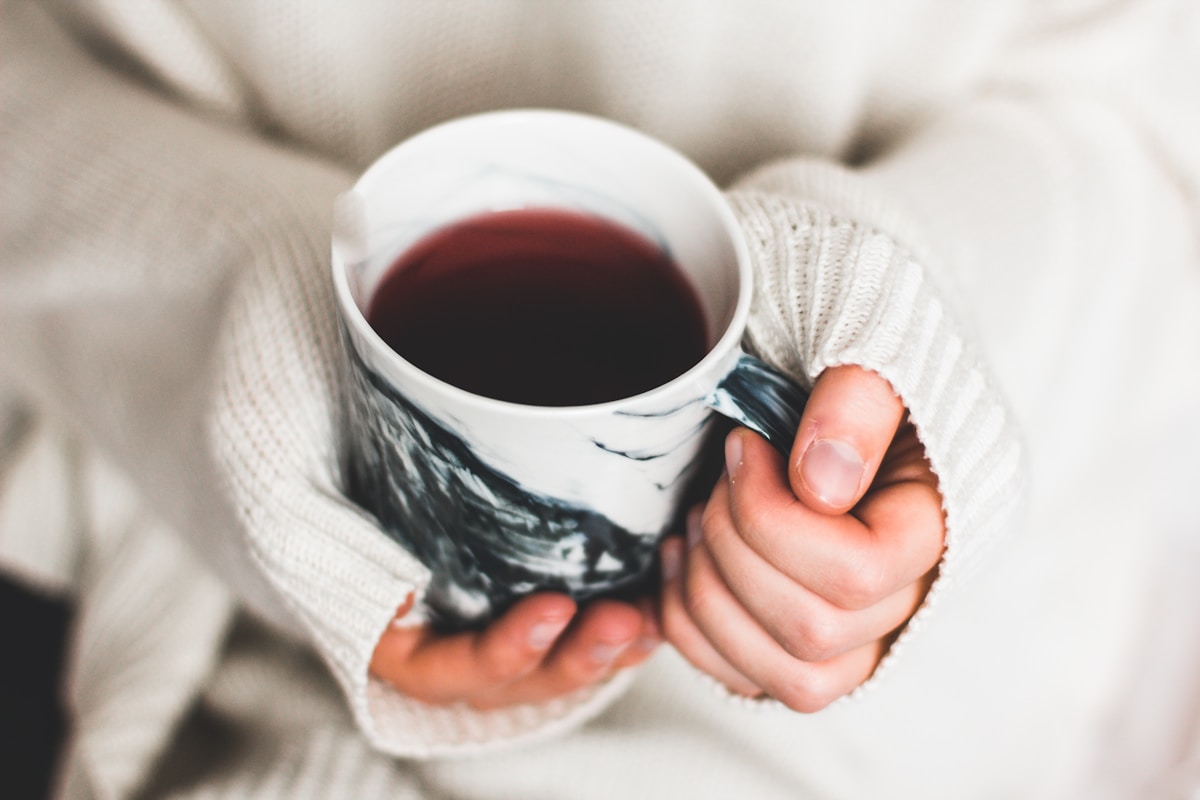 A person wrapped in a soft sweater cradling a warm mug, a calming image of the mind and body healing on their own timelines