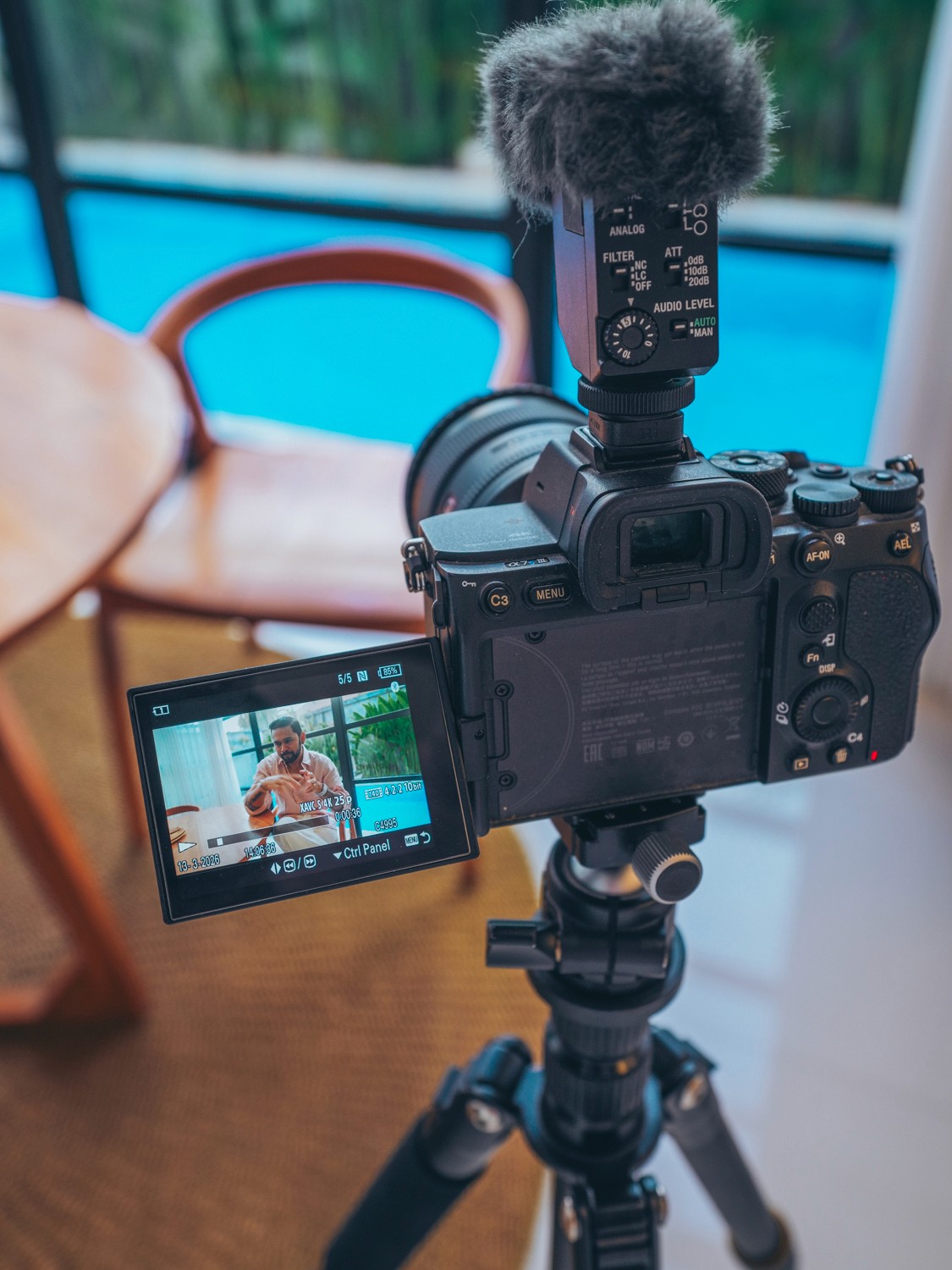 High-angle fish-eye portrait of a woman in a pink top near flowering bushes.