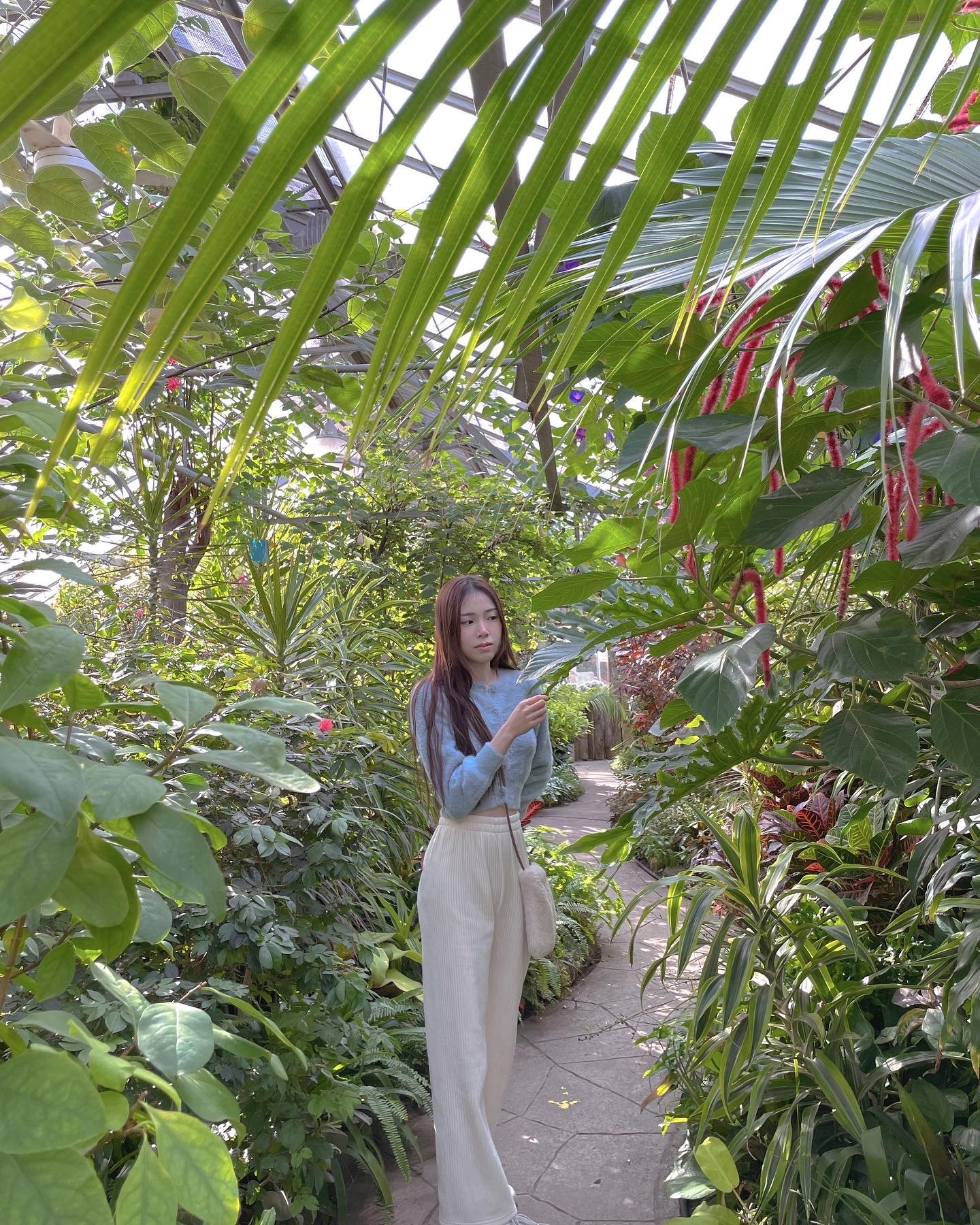 Picture of Elizabeth Chen standing in botantical garden surrounded by leaves