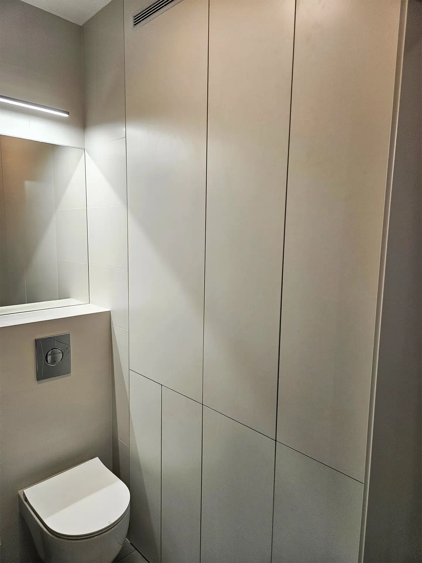 Minimalistyczna, wysoka zabudowa szafkowa w łazience w kolorze piaskowym.