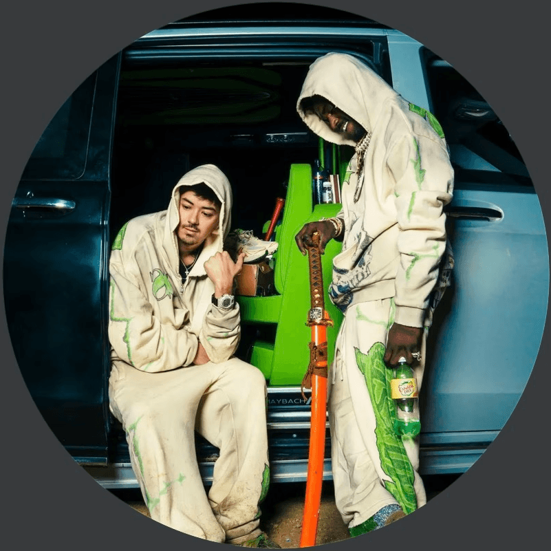 A woman with a red bow headband and bright orange and blue clothing poses against a teal and orange geometric background. Her expression is confident.
