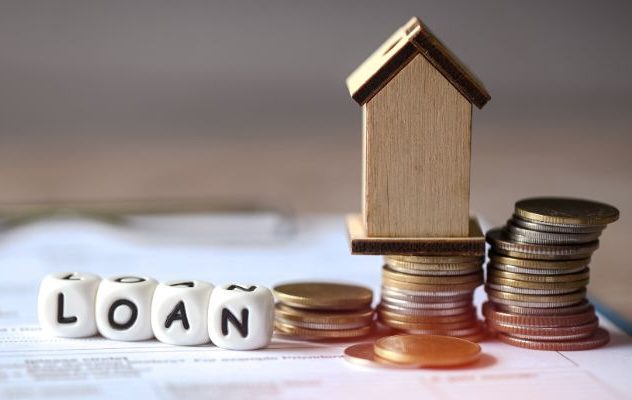 Loan dice, miniature house, and stacks of coins.