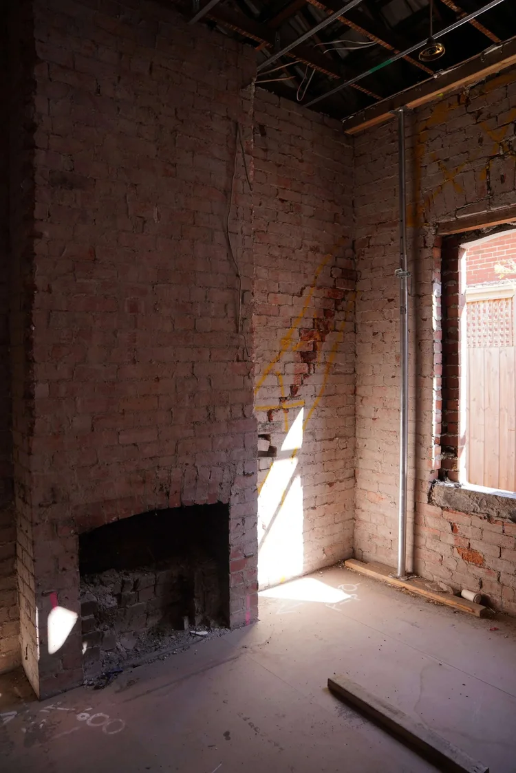 Exposed brick wall interior renovation with fireplace and window.