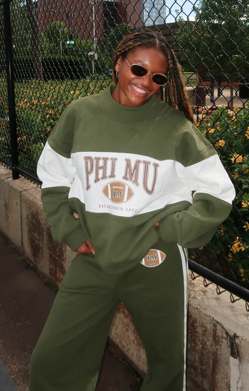 Alex Ruff wearing an olive-and-cream Phi Mu football sweatshirt with matching wide-leg pants.