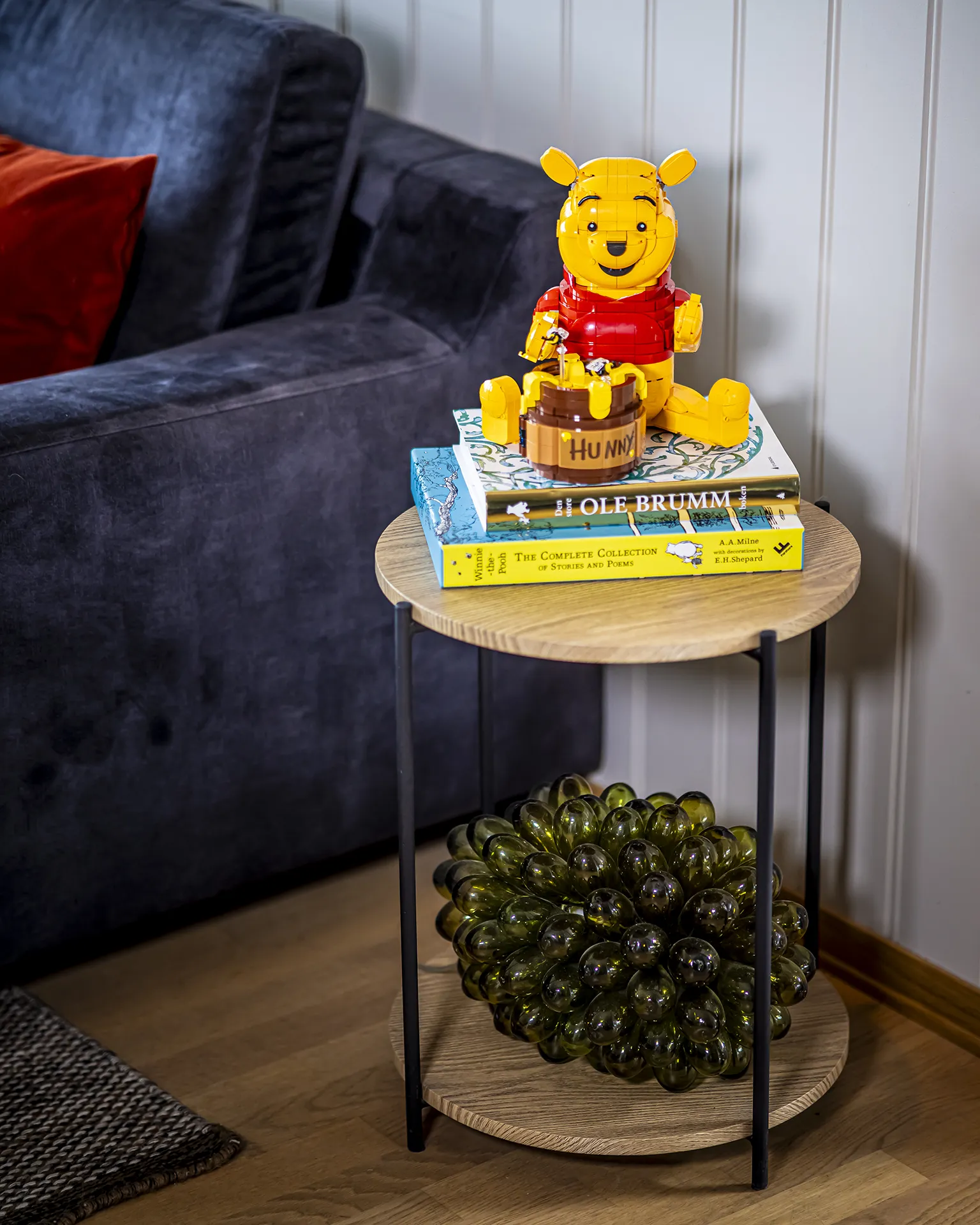 LEGO® Ole Brumm figur med honningkrukke plassert oppå bøker på sidebord