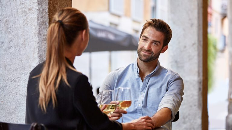 ein mann und eine frau sitzen draußen und trinken etwas gemeinsam