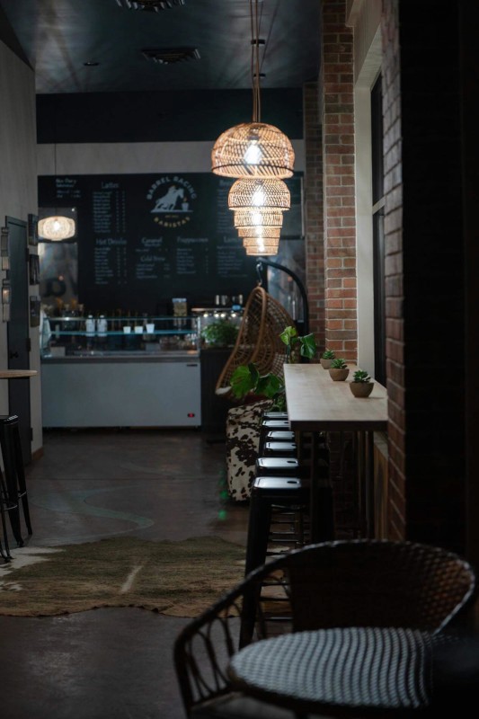 A close-up shot of a fork twirling strands of creamy white pasta, possibly carbonara or cacio e pepe, heavily garnished with dark black pepper or truffle shavings, against a stark white background.