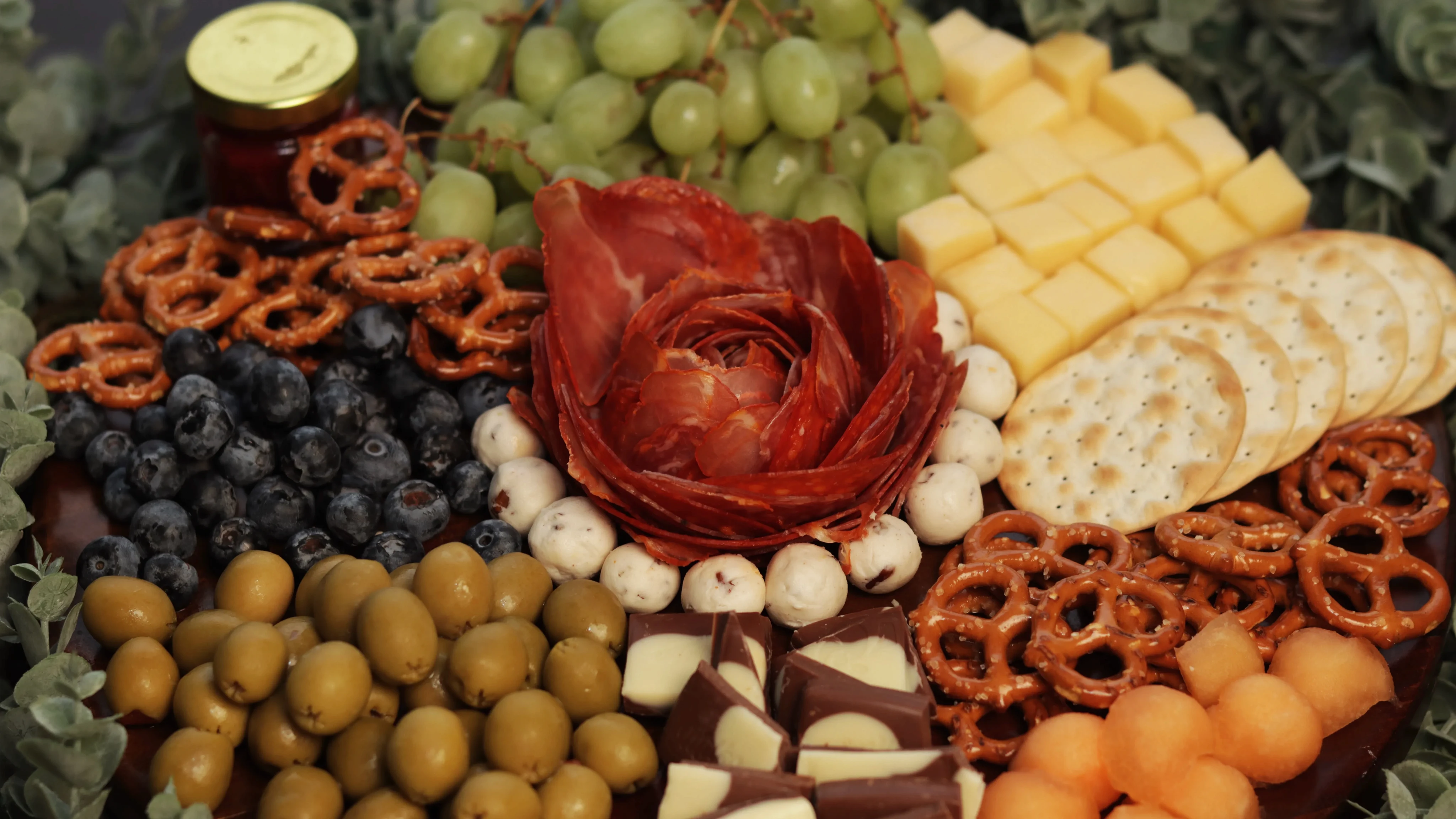 Tabla de charcutería con quesos, frutas y pretzels
