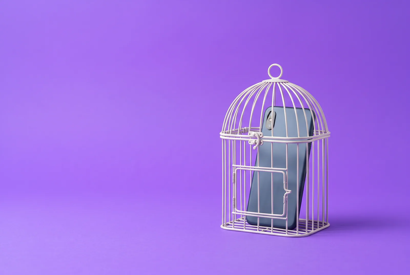 How to quit porn as a teenager: a smartphone shown from the back, locked inside a small white birdcage on a lilac backdrop