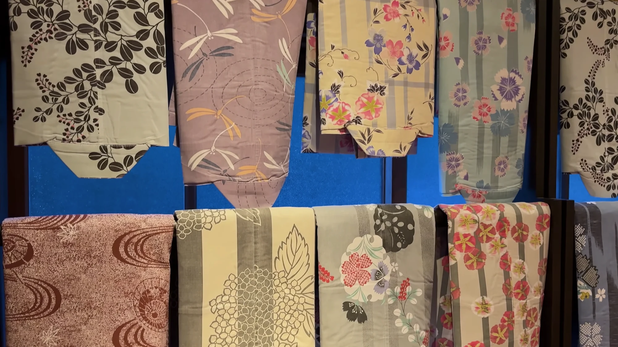 Yukata fabrics in floral and botanical patterns hanging in a Kinosaki shop.