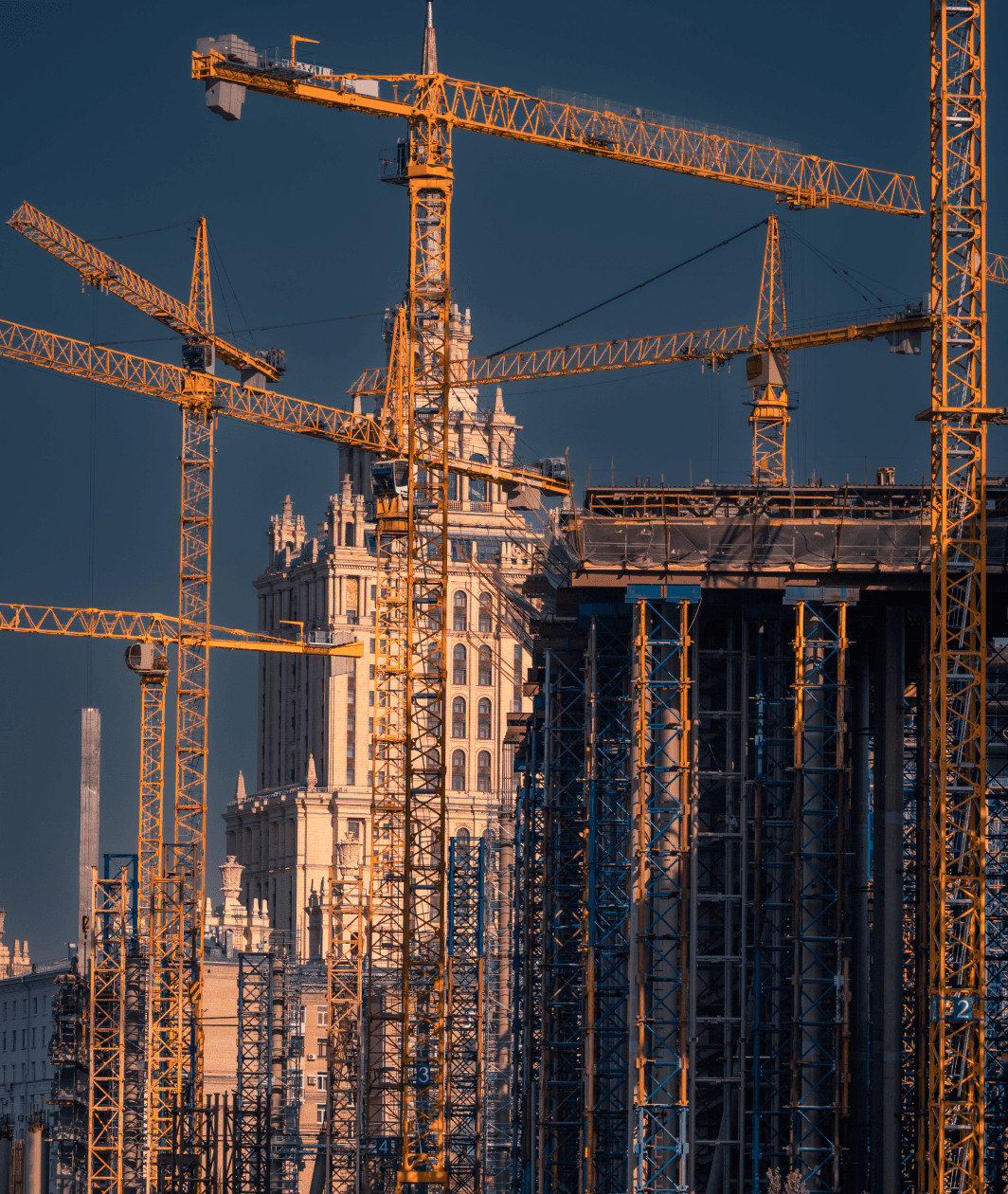 Construction workers wearing hard hats and blue overalls working on a residential brick building site.