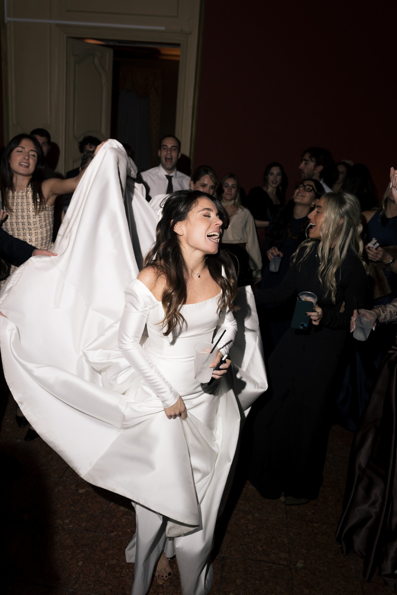 Sposa in abito bianco mikado e velo lungo, sorridente tra gli ospiti durante il ricevimento al Circolo di Lettura di Parma