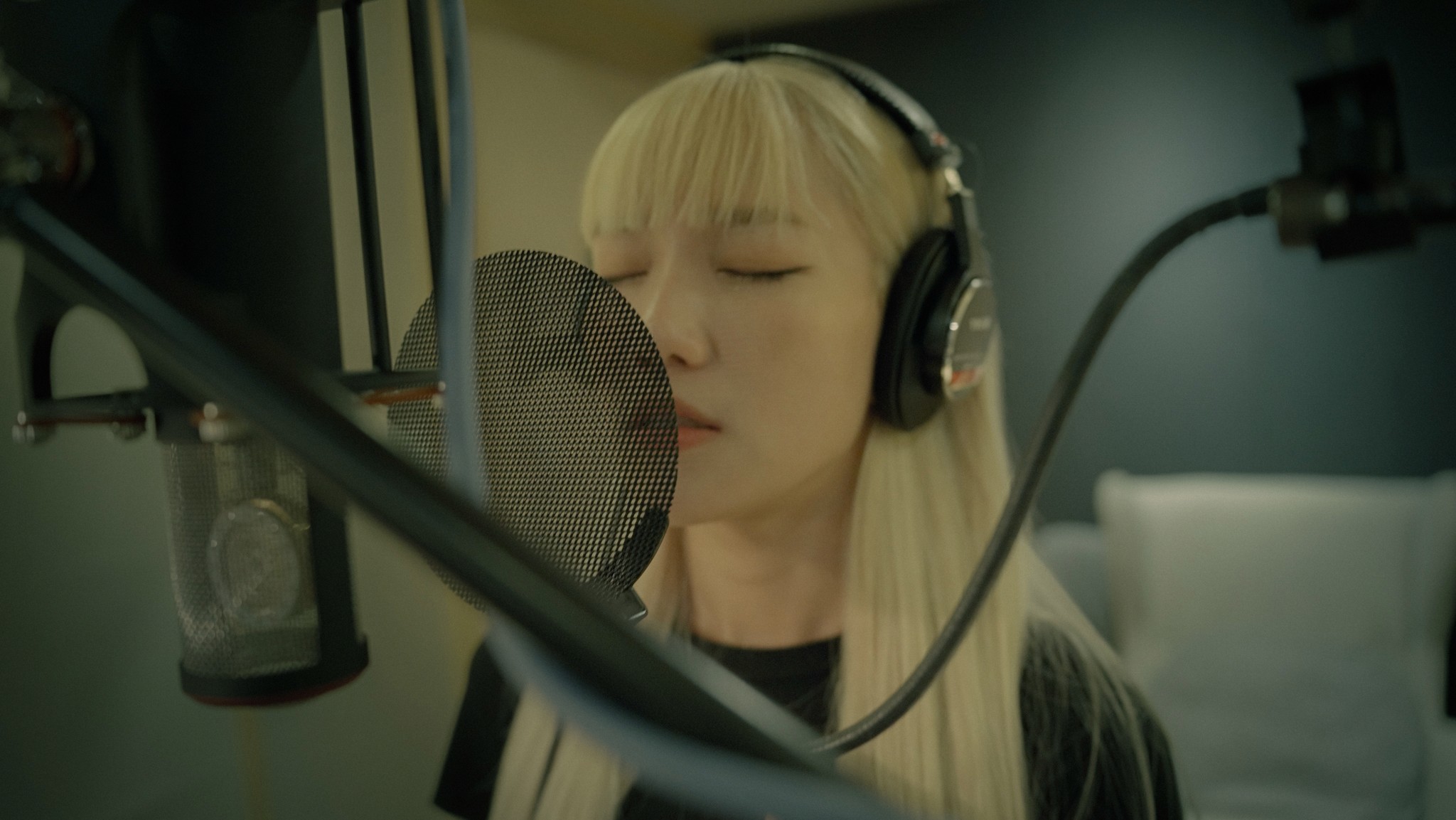 Silhouette of a person with a camera walking towards vibrant orange light under dim blue streetlights on a misty road at night. Mysterious and atmospheric.