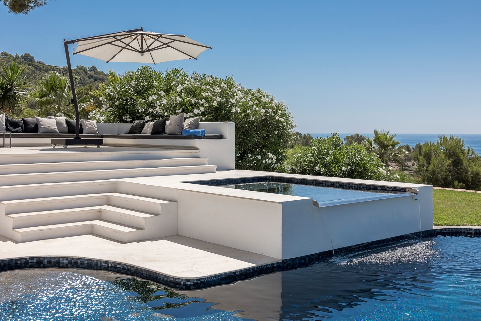 Jacuzzi at the exclusive luxury Ibiza villa, with a steaming hot tub beside the pool area and loungers—a private VIP estate property holiday retreat for wellness, weddings and events.