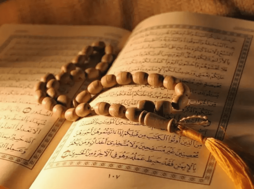 Quran and prayer beads in warm light